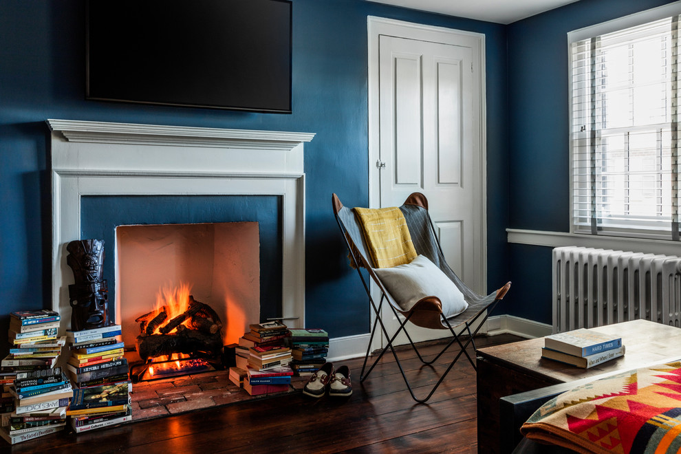 This is an example of a small transitional bedroom in Philadelphia with blue walls, dark hardwood floors, a standard fireplace and a plaster fireplace surround.