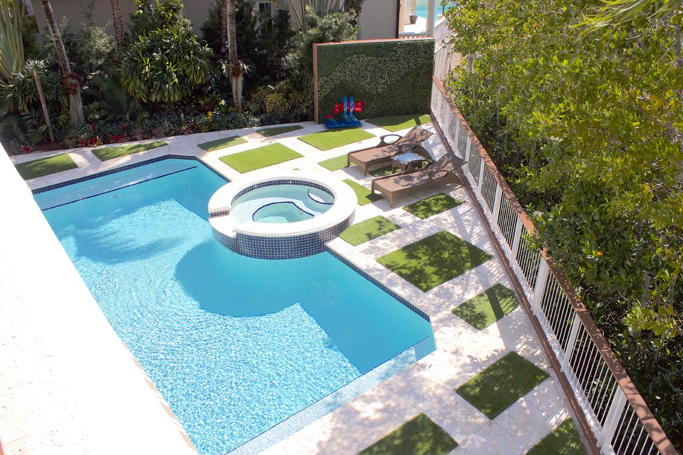 This is an example of a mid-sized tropical backyard rectangular pool in Miami with a hot tub and concrete pavers.