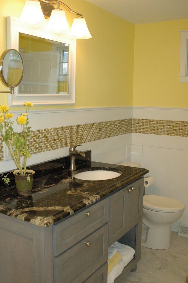This is an example of a mid-sized transitional 3/4 bathroom in Boston with furniture-like cabinets, grey cabinets, a freestanding tub, yellow walls, porcelain floors, an undermount sink, marble benchtops and beige floor.