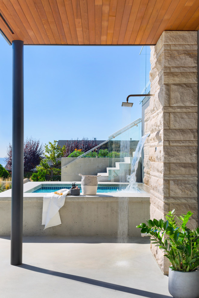 Photo of an expansive contemporary front yard rectangular aboveground pool in Vancouver with concrete slab and a hot tub.