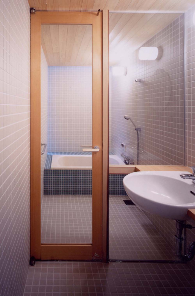 Modern inredning av ett litet beige beige en-suite badrum, med öppna hyllor, vita skåp, ett japanskt badkar, en dusch/badkar-kombination, en toalettstol med hel cisternkåpa, vit kakel, porslinskakel, vita väggar, ljust trägolv, ett nedsänkt handfat, träbänkskiva, beiget golv och dusch med gångjärnsdörr