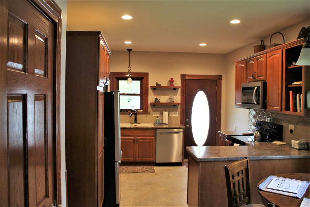 Example of a mid-sized mountain style l-shaped vinyl floor and beige floor eat-in kitchen design with a farmhouse sink, raised-panel cabinets, medium tone wood cabinets, laminate countertops, beige backsplash, cement tile backsplash, stainless steel appliances, a peninsula and beige countertops
