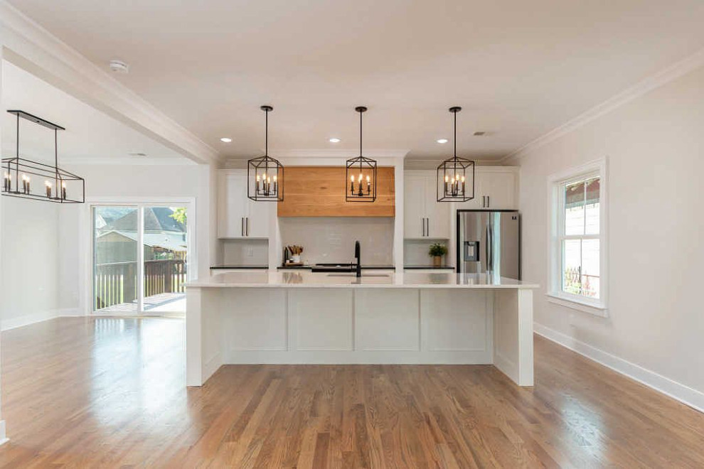 Inspiration for a large transitional galley medium tone wood floor and brown floor open concept kitchen remodel with an undermount sink, shaker cabinets, white cabinets, quartz countertops, white backsplash, ceramic backsplash, stainless steel appliances, an island and white countertops