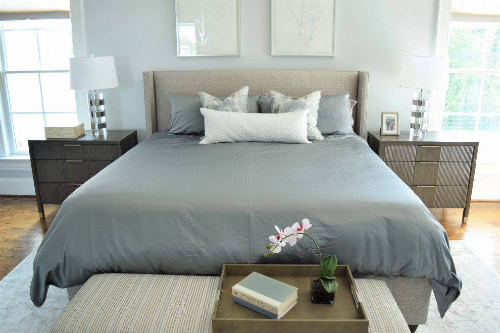 Идея дизайна: большая хозяйская спальня в стиле модернизм с серыми стенами, паркетным полом среднего тона, двусторонним камином, фасадом камина из штукатурки и коричневым полом