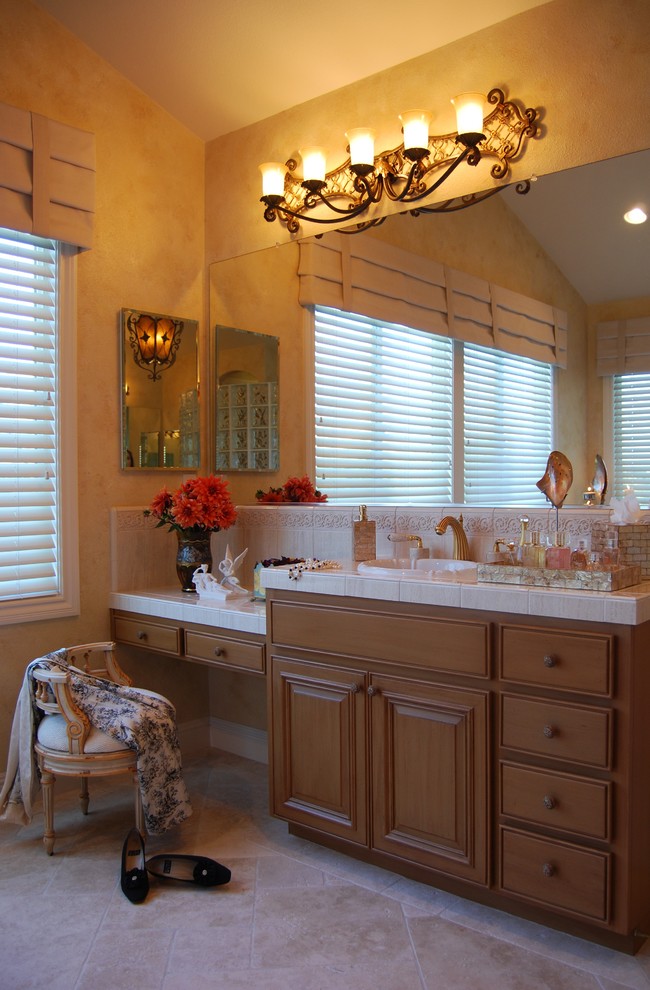 Inspiration for a large mediterranean master beige tile and porcelain tile marble floor corner bathtub remodel in San Francisco with an undermount sink, raised-panel cabinets, distressed cabinets, tile countertops, a two-piece toilet and multicolored walls