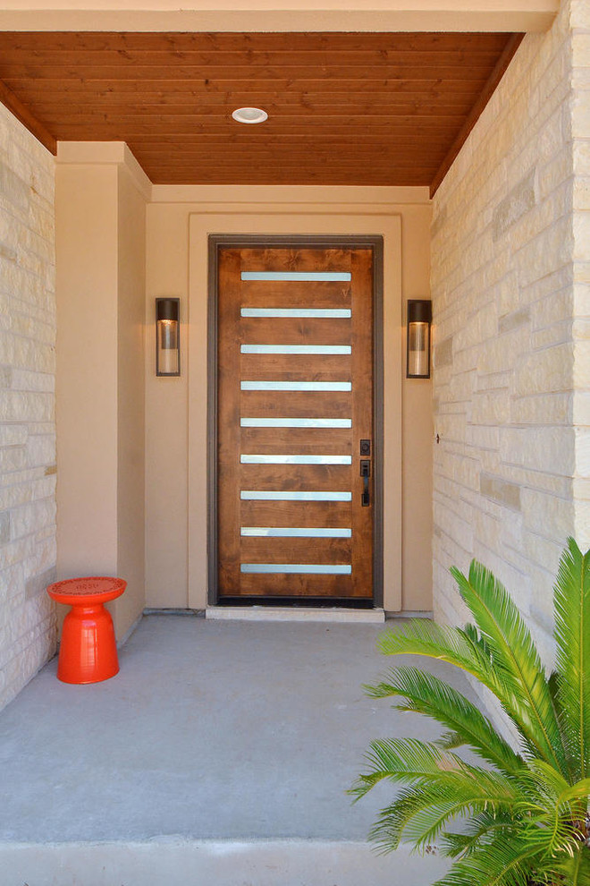 Photo of a large contemporary front door in Austin with beige walls, concrete floors, a single front door, a medium wood front door and grey floor.