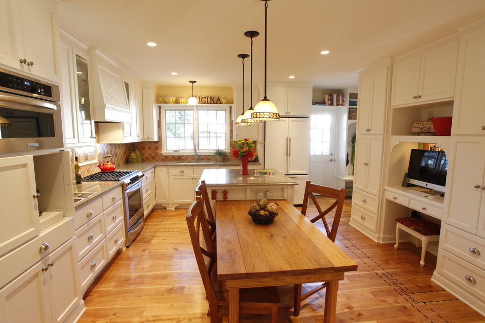 This is an example of a mid-sized traditional l-shaped eat-in kitchen in Minneapolis with stainless steel appliances, with island, flat-panel cabinets, white cabinets, granite benchtops, multi-coloured splashback, terra-cotta splashback, an undermount sink and light hardwood floors.