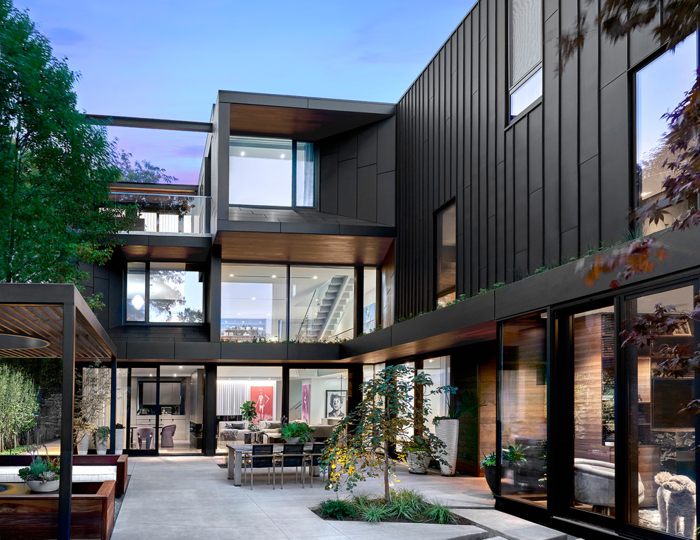 Photo of a large contemporary three-storey black house exterior in Chicago with metal siding, a flat roof and a green roof.