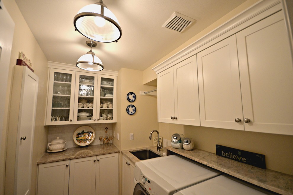 Photo of a small traditional galley utility room in Boise with an undermount sink, recessed-panel cabinets, granite benchtops, beige walls, light hardwood floors and a side-by-side washer and dryer.
