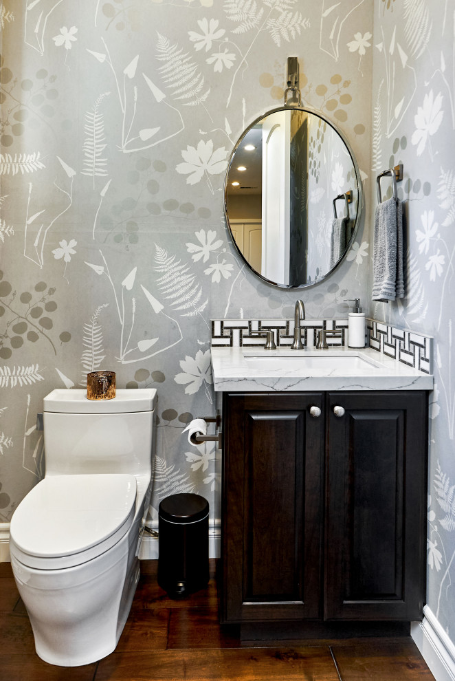 Small classic cloakroom in San Francisco with raised-panel cabinets, brown cabinets, a one-piece toilet, black and white tiles, stone tiles, grey walls, dark hardwood flooring, a submerged sink, engineered stone worktops, brown floors, grey worktops, a built in vanity unit and wallpapered walls.