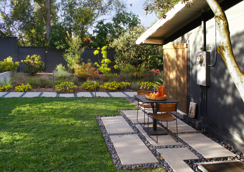 Mid-sized midcentury front yard partial sun driveway in Los Angeles with a garden path, concrete pavers and a metal fence for winter.