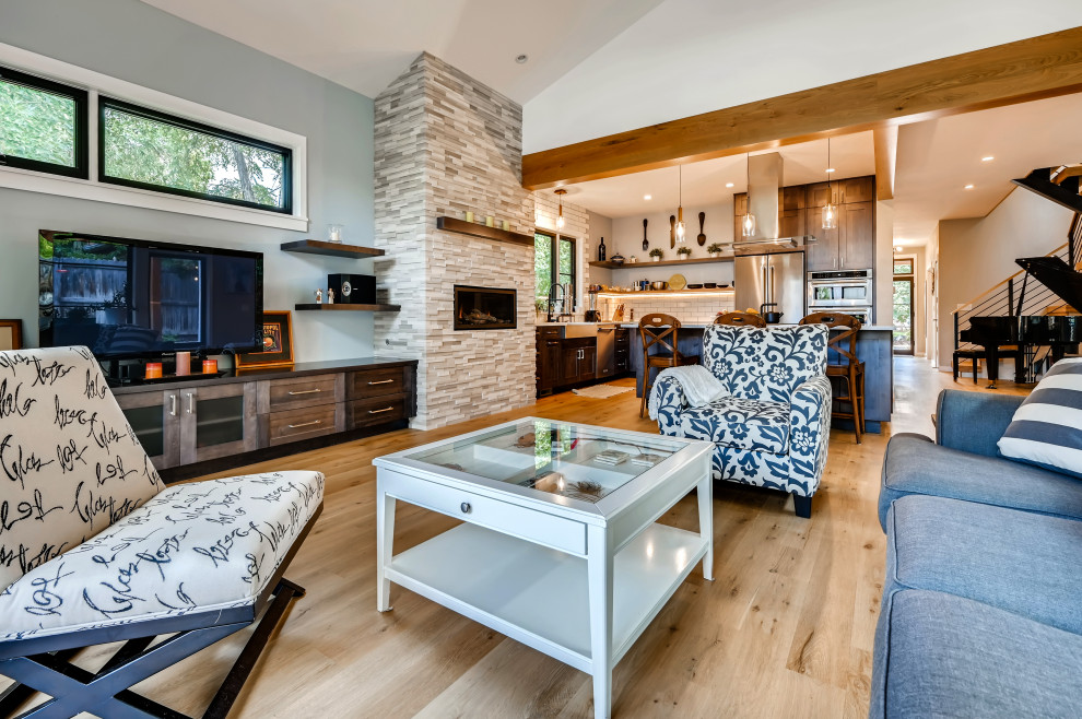 Mittelgroßes, Offenes Modernes Wohnzimmer mit beiger Wandfarbe, hellem Holzboden, Kaminumrandung aus gestapelten Steinen, freistehendem TV, braunem Boden und freigelegten Dachbalken in Denver