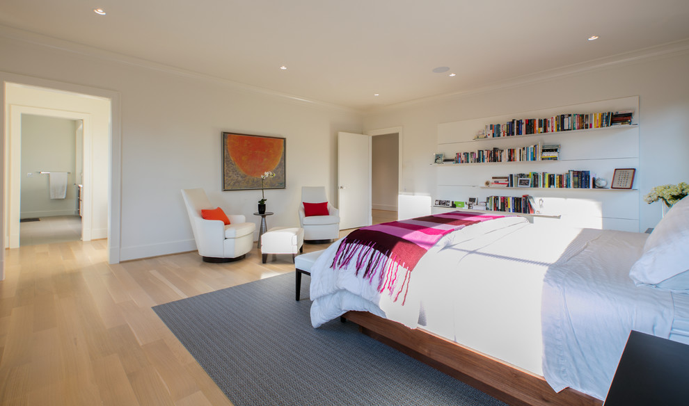 This is an example of a large modern master bedroom in DC Metro with white walls and light hardwood floors.