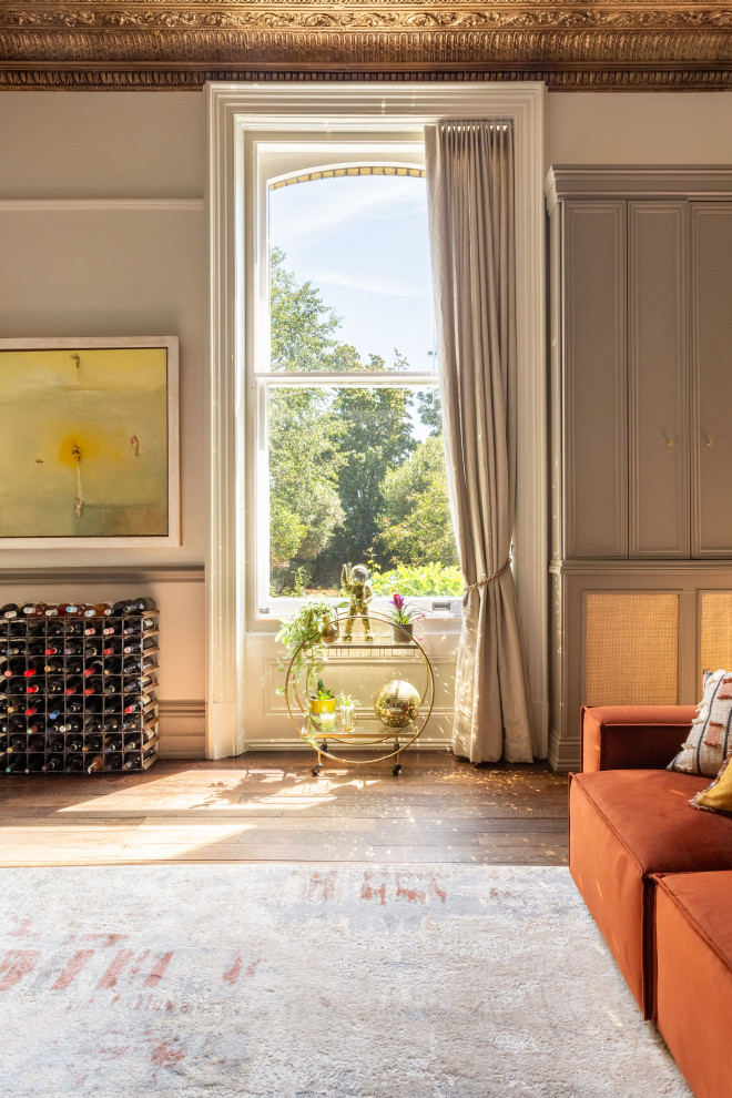 Design ideas for a large bohemian living room in Sussex with beige walls, dark hardwood flooring, a plastered fireplace surround, a wall mounted tv, brown floors and a wallpapered ceiling.
