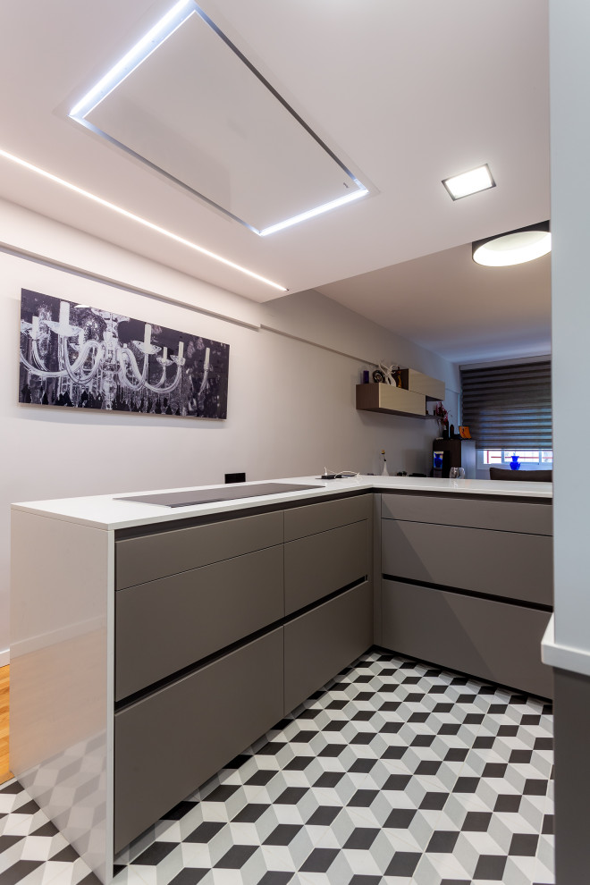 Photo of a mid-sized contemporary u-shaped open plan kitchen in Barcelona with flat-panel cabinets, black appliances, porcelain floors, a peninsula, multi-coloured floor and beige benchtop.