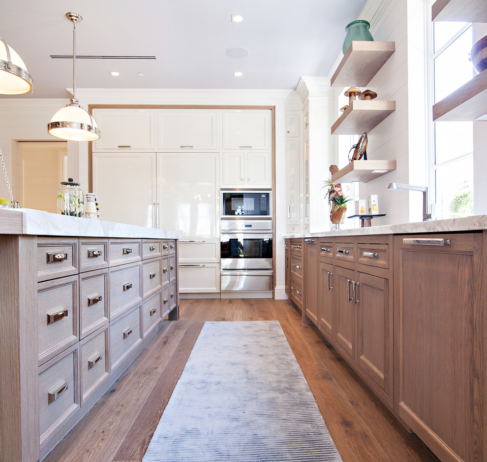 Kitchen - huge transitional medium tone wood floor kitchen idea in Miami with an undermount sink, shaker cabinets, white cabinets, marble countertops, white backsplash, stone slab backsplash, white appliances and an island