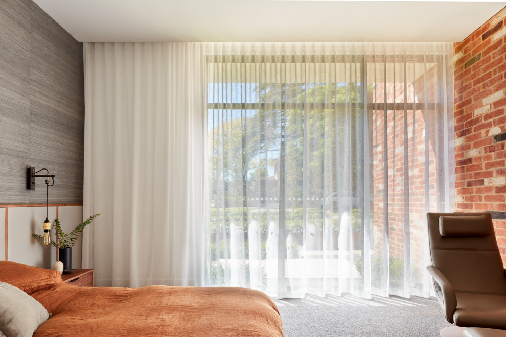 На фото: большая хозяйская спальня в современном стиле с ковровым покрытием, разноцветным полом и кирпичными стенами с
