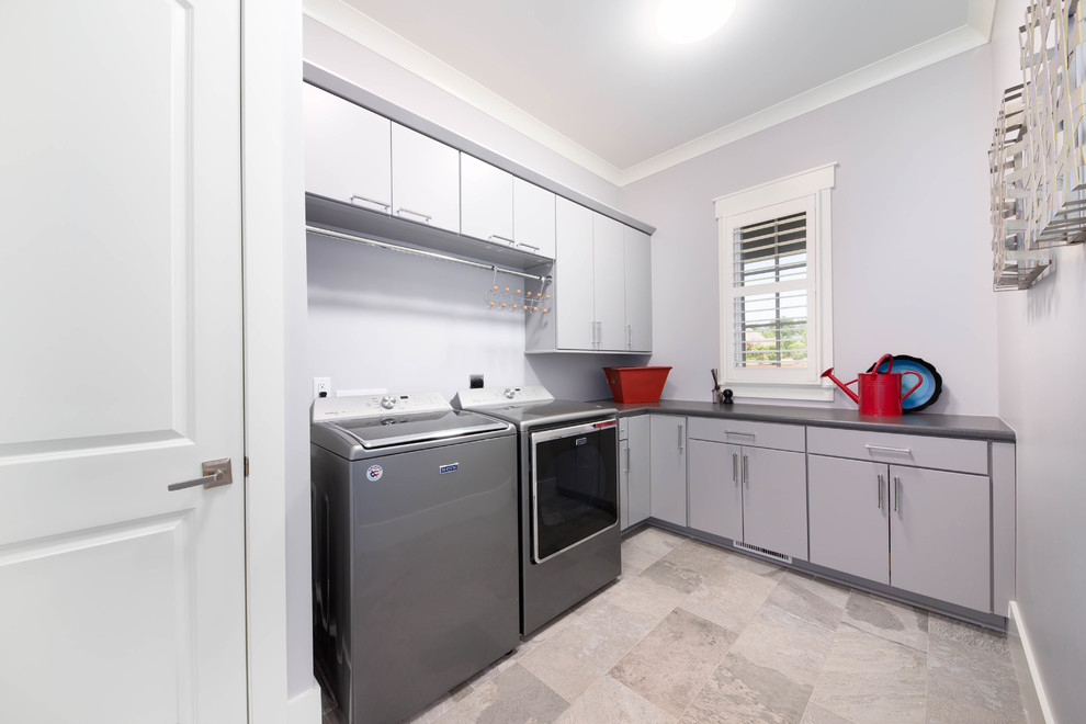 This is an example of a large arts and crafts l-shaped dedicated laundry room in Other with flat-panel cabinets, grey cabinets, laminate benchtops, grey walls, ceramic floors, a side-by-side washer and dryer, green floor and grey benchtop.