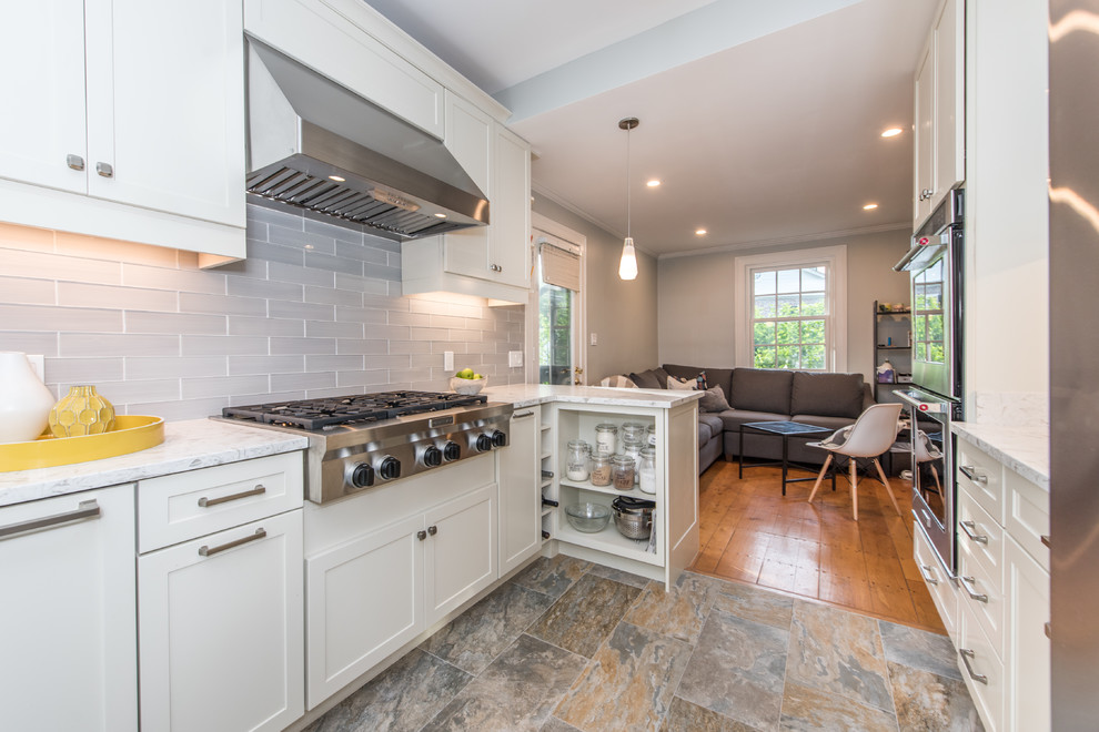 Mid-sized contemporary galley eat-in kitchen in DC Metro with an undermount sink, recessed-panel cabinets, white cabinets, quartz benchtops, grey splashback, subway tile splashback, stainless steel appliances, slate floors, a peninsula, multi-coloured floor and white benchtop.