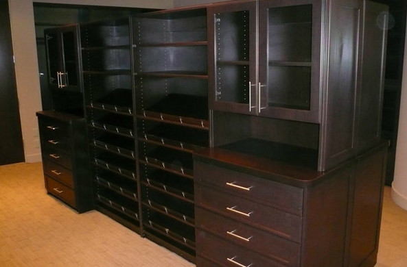 This is an example of a mid-sized contemporary gender-neutral walk-in wardrobe in Other with flat-panel cabinets, dark wood cabinets, carpet and beige floor.