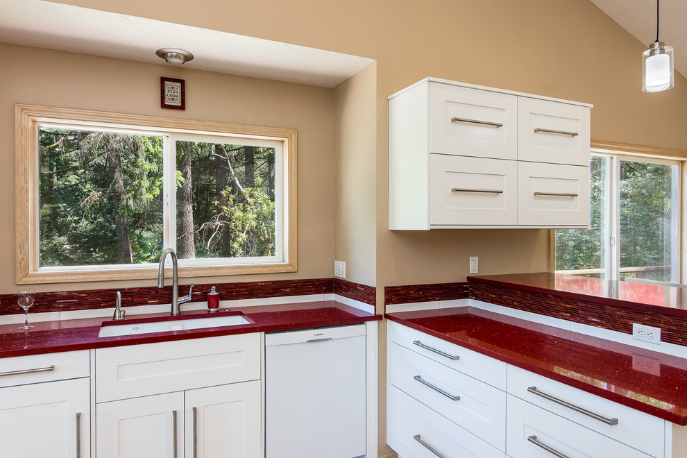 Mid-sized traditional l-shaped eat-in kitchen in Portland with an undermount sink, shaker cabinets, white cabinets, quartz benchtops, red splashback, glass sheet splashback, stainless steel appliances, light hardwood floors, with island, brown floor and red benchtop.