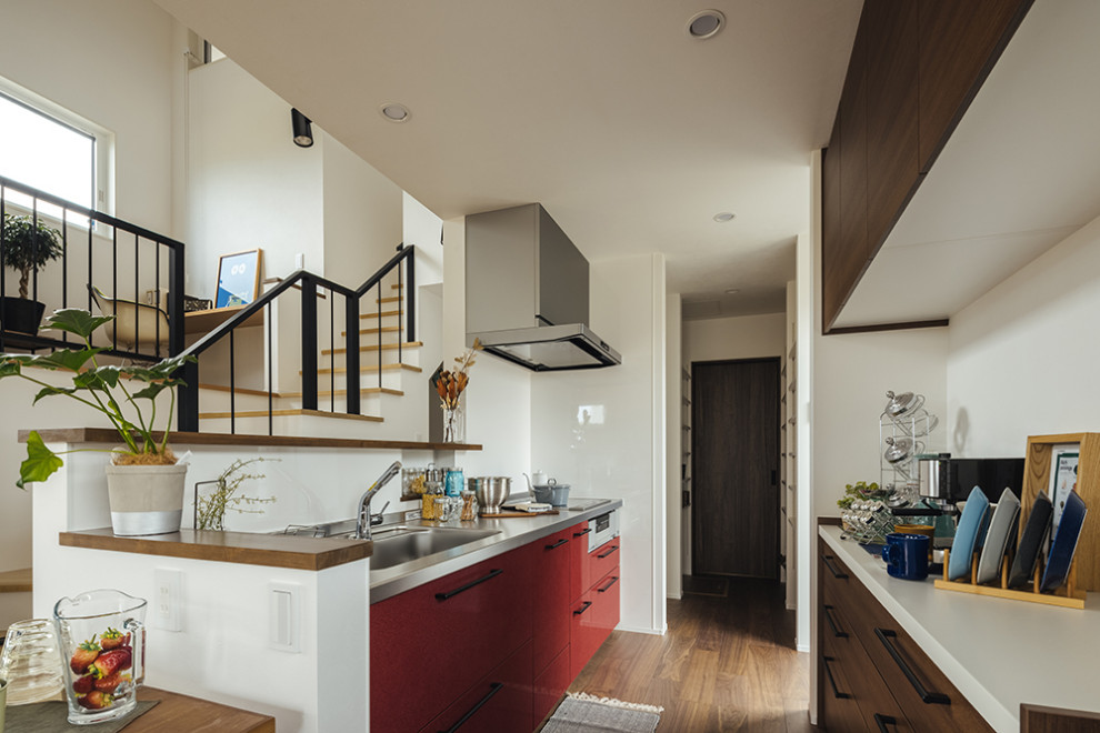 Aménagement d'une arrière-cuisine linéaire industrielle de taille moyenne avec une crédence rouge, parquet foncé, un sol marron et un plafond en papier peint.