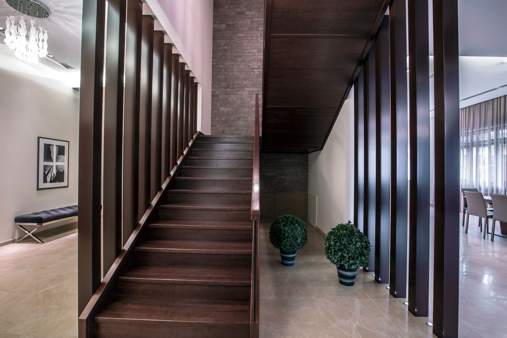 Imagen de escalera en U grande con escalones de madera, contrahuellas de madera y barandilla de vidrio