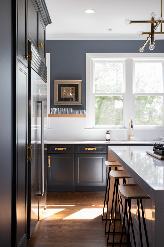 Example of a small transitional l-shaped medium tone wood floor and brown floor eat-in kitchen design in Minneapolis with an undermount sink, recessed-panel cabinets, brown cabinets, quartz countertops, white backsplash, stone slab backsplash, an island, white countertops and stainless steel appliances