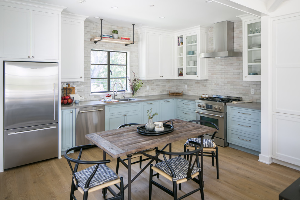 Photo of a country eat-in kitchen in Los Angeles with an undermount sink, shaker cabinets, blue cabinets, grey splashback, subway tile splashback, stainless steel appliances, medium hardwood floors, no island, brown floor and grey benchtop.