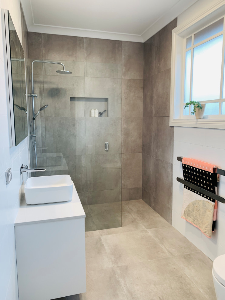 Photo of a medium sized contemporary ensuite bathroom in Other with beaded cabinets, white cabinets, a walk-in shower, all types of toilet, multi-coloured tiles, porcelain tiles, multi-coloured walls, porcelain flooring, a vessel sink, engineered stone worktops, grey floors, an open shower, white worktops, a wall niche, a single sink and a floating vanity unit.