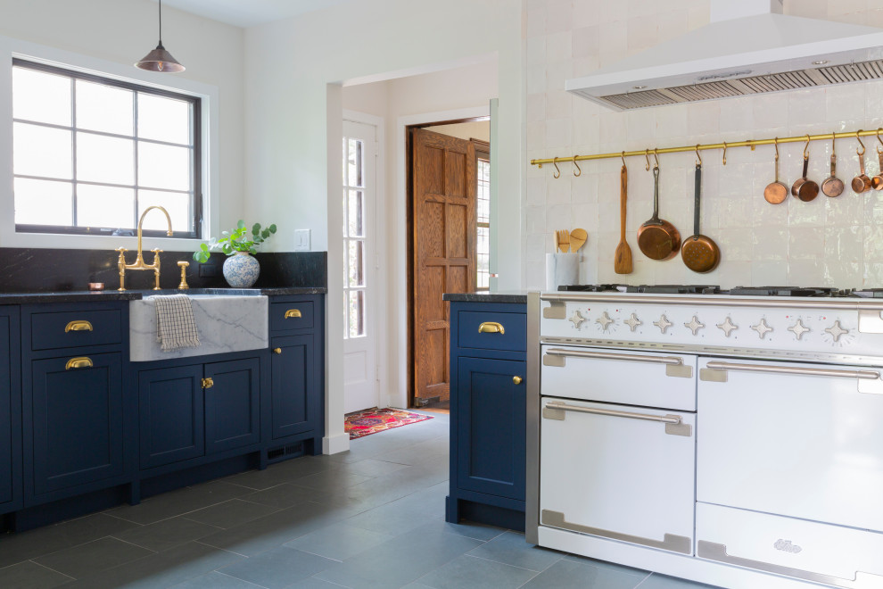 Inspiration for a small french country u-shaped slate floor and gray floor enclosed kitchen remodel in New York with a farmhouse sink, shaker cabinets, blue cabinets, granite countertops, white backsplash, white appliances, no island and black countertops