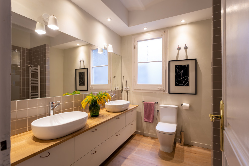 Photo of a large contemporary master bathroom in Other with furniture-like cabinets, white cabinets, a corner shower, an urinal, beige walls, medium hardwood floors, a vessel sink, wood benchtops, brown floor, an open shower and brown benchtops.