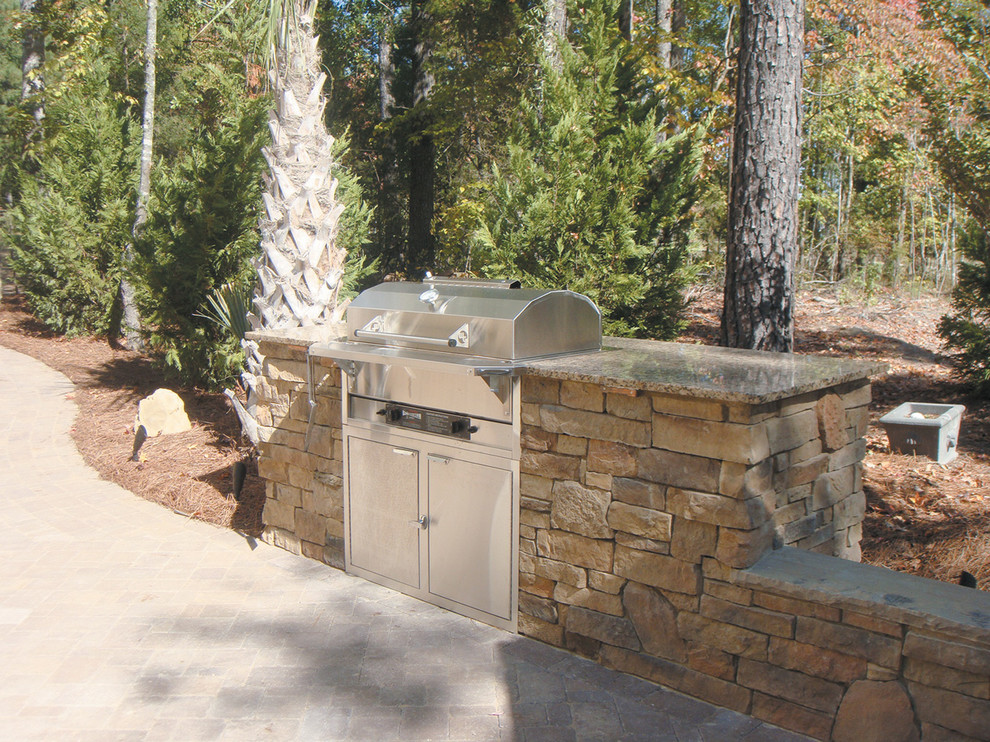 This is an example of a small traditional backyard patio in Toronto with an outdoor kitchen, natural stone pavers and no cover.