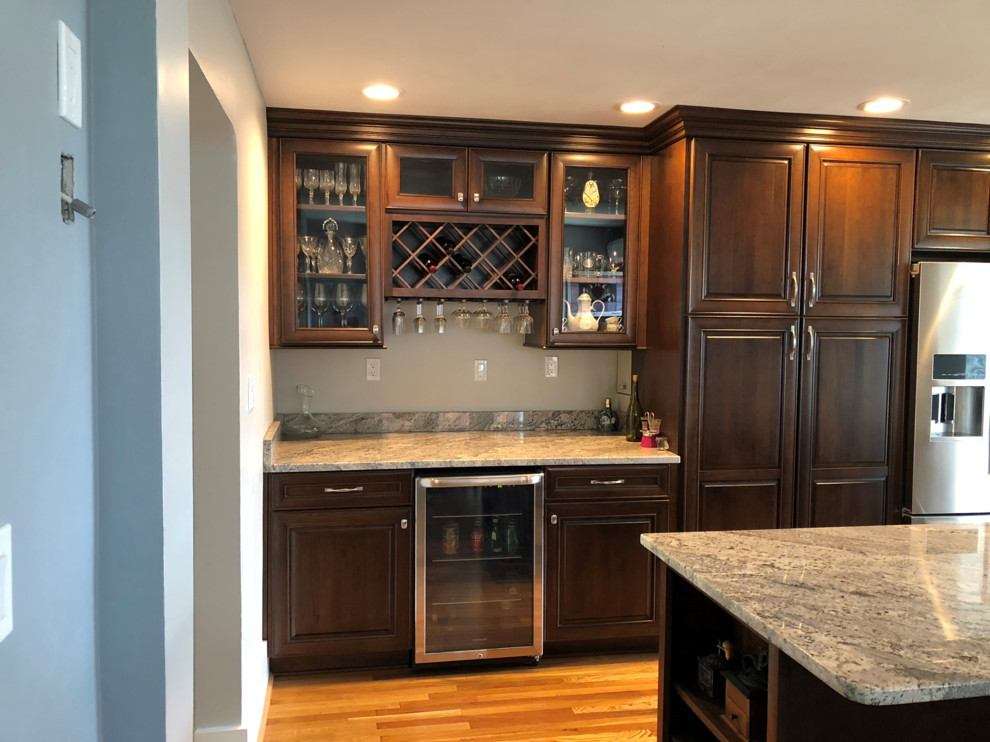 Inspiration for a mid-sized timeless l-shaped light wood floor and brown floor eat-in kitchen remodel with an undermount sink, raised-panel cabinets, dark wood cabinets, granite countertops, multicolored backsplash, ceramic backsplash, stainless steel appliances, an island and multicolored countertops