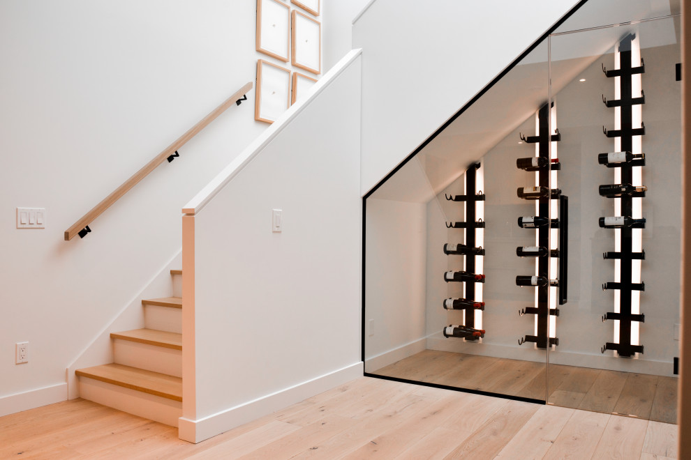 Cette image montre une petite cave à vin minimaliste avec parquet clair, des casiers et un sol beige.