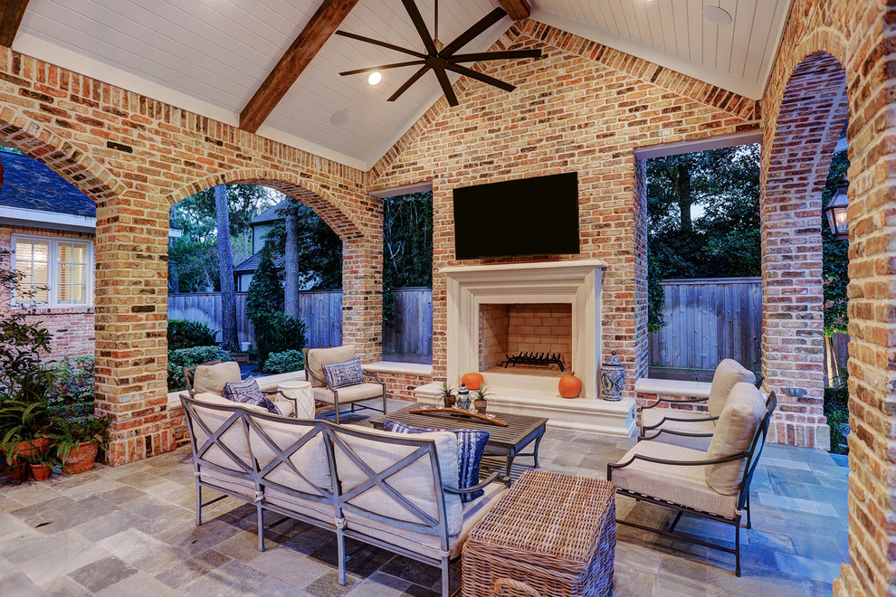 Inspiration for a mid-sized traditional backyard patio in Houston with an outdoor kitchen, natural stone pavers and a roof extension.