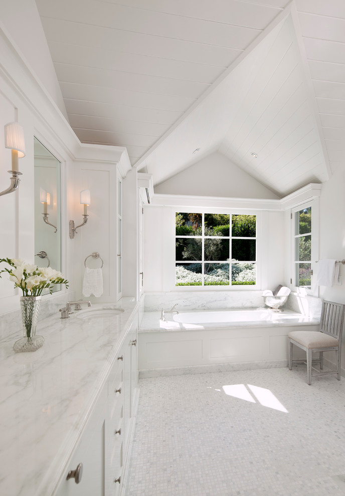 Inspiration for a country bathroom in Santa Barbara with shaker cabinets, white cabinets, marble benchtops, a drop-in tub, white walls, ceramic floors and an undermount sink.