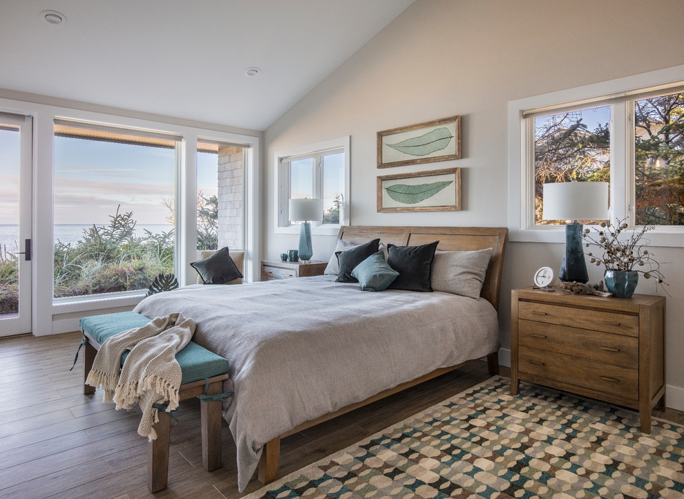 This is an example of a mid-sized beach style master bedroom in Portland with beige walls, porcelain floors and brown floor.