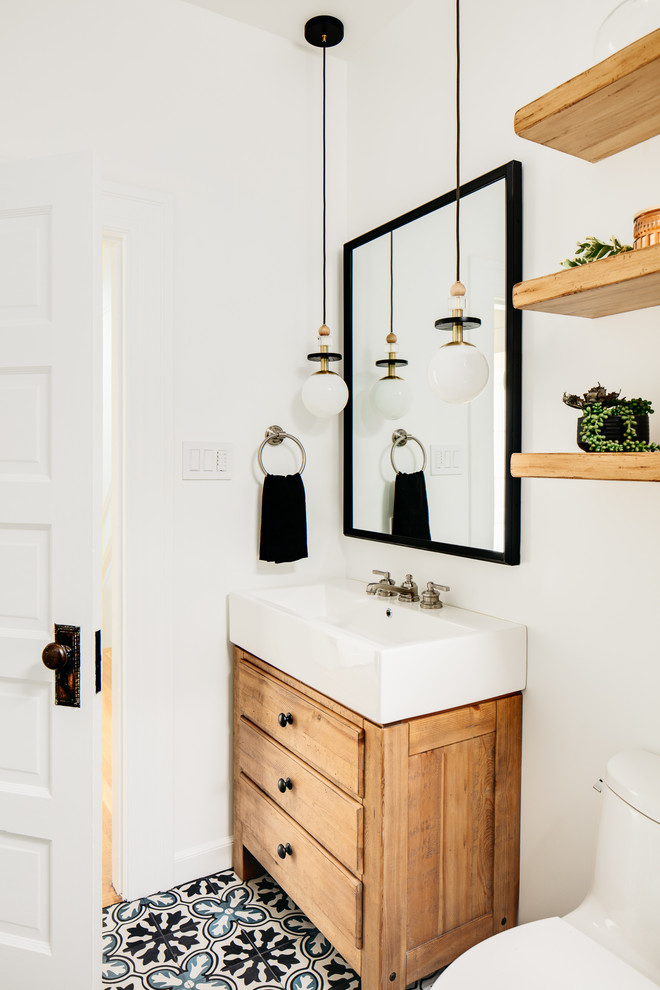 This is an example of a small scandinavian powder room in San Francisco with furniture-like cabinets, medium wood cabinets, white walls and multi-coloured floor.