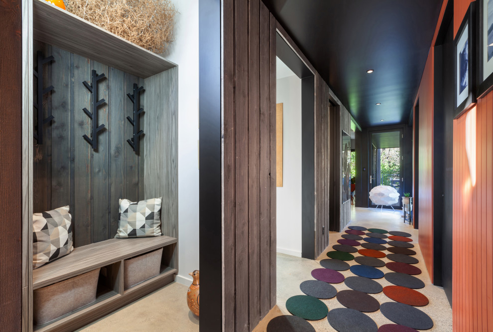Réalisation d'un petit couloir minimaliste en bois avec un mur marron, sol en béton ciré et un sol gris.