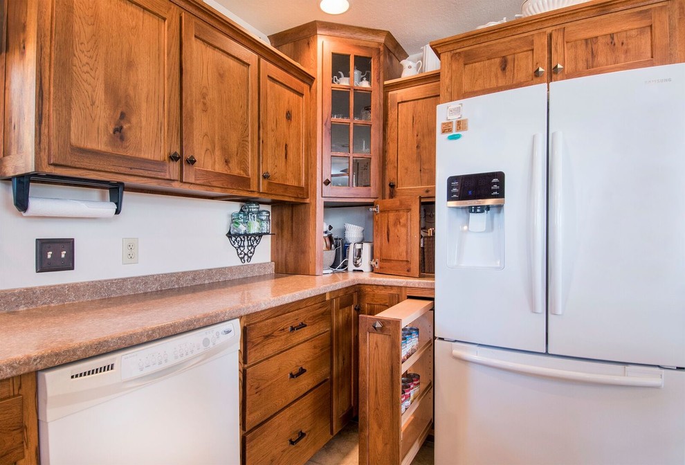 Example of a mid-sized mountain style u-shaped laminate floor eat-in kitchen design in Cincinnati with a drop-in sink, recessed-panel cabinets, medium tone wood cabinets, wood countertops, white appliances, an island and brown countertops