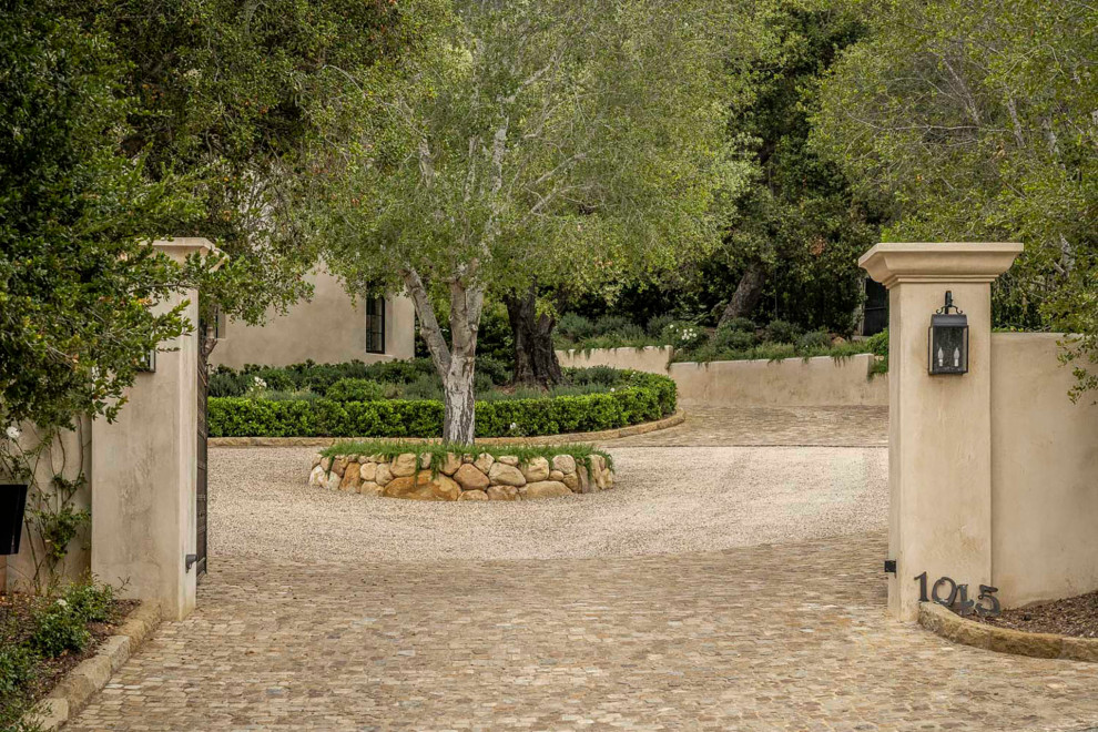 This is an example of a large mediterranean front yard driveway in Santa Barbara with natural stone pavers.