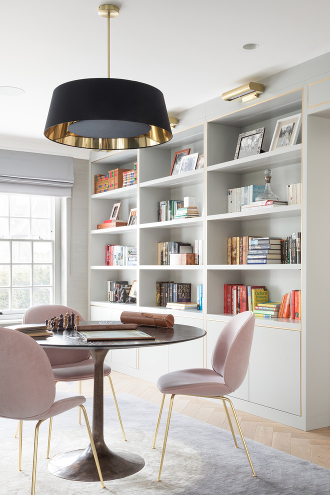 Transitional home office in London with a library, light hardwood floors, beige floor and grey walls.