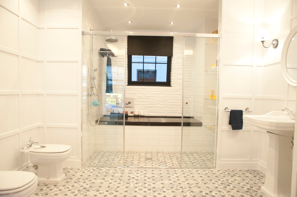 Modelo de cuarto de baño principal escandinavo de tamaño medio con bañera empotrada, combinación de ducha y bañera, bidé, paredes blancas, suelo de baldosas de cerámica y lavabo con pedestal