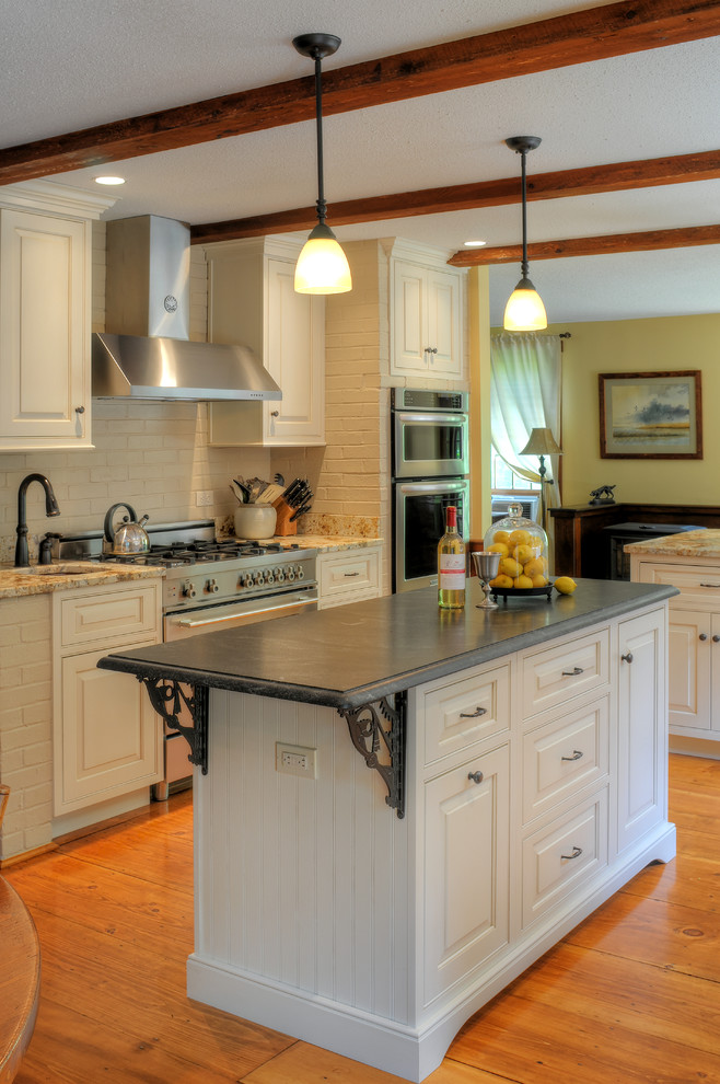 Example of a mid-sized transitional u-shaped medium tone wood floor and brown floor eat-in kitchen design in Boston with white cabinets, granite countertops, stainless steel appliances, an island, a farmhouse sink and raised-panel cabinets