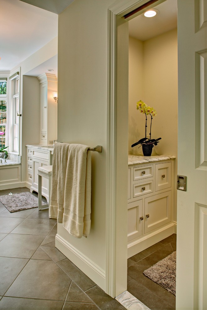 This is an example of a mid-sized traditional master bathroom in New York with beaded inset cabinets, white cabinets, an alcove shower, beige tile, white tile, marble, white walls, porcelain floors, an undermount sink, marble benchtops, beige floor and a hinged shower door.