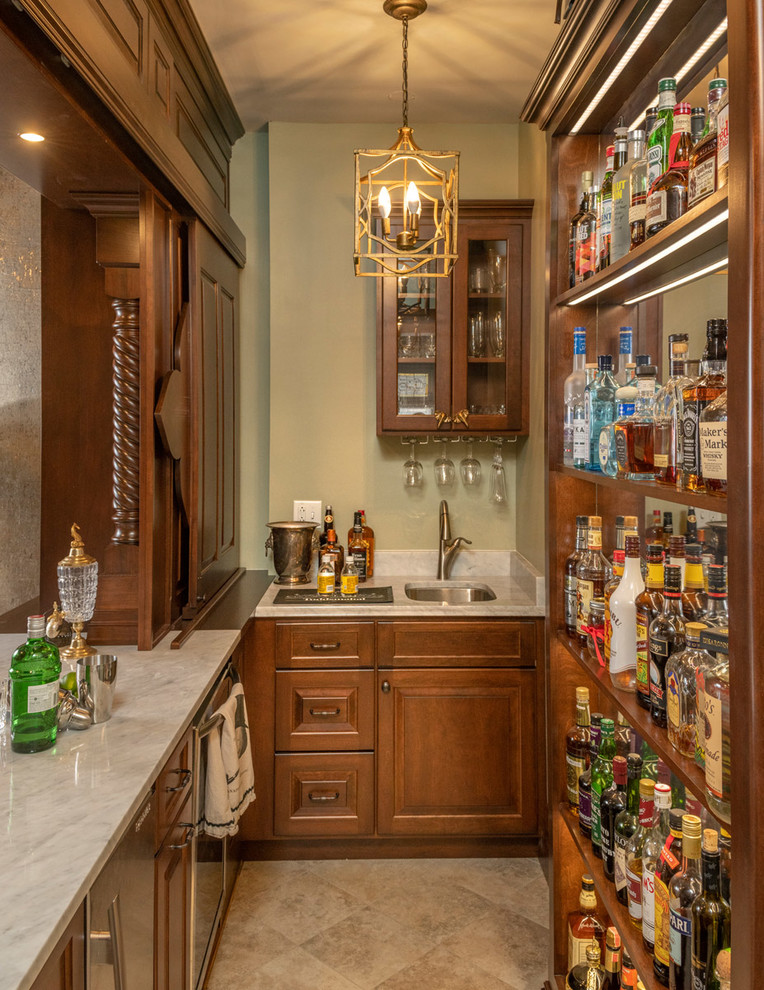 This is an example of a mid-sized traditional single-wall wet bar in Other with a drop-in sink, glass-front cabinets, medium wood cabinets, marble benchtops, medium hardwood floors, brown floor and brown benchtop.