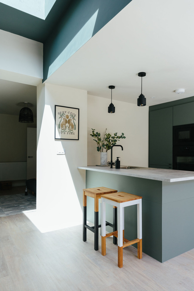 Foto på ett mellanstort funkis kök, med gröna skåp, svarta vitvaror och en köksö