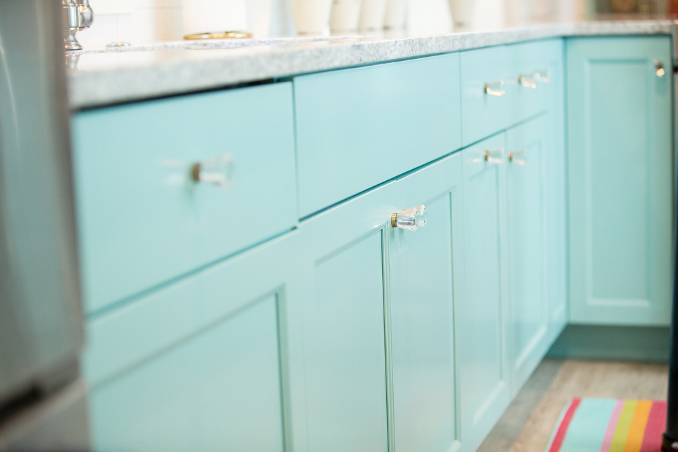 Photo of a small beach style l-shaped eat-in kitchen in Other with an undermount sink, flat-panel cabinets, turquoise cabinets, quartz benchtops, white splashback, ceramic splashback, stainless steel appliances, vinyl floors, with island and grey floor.