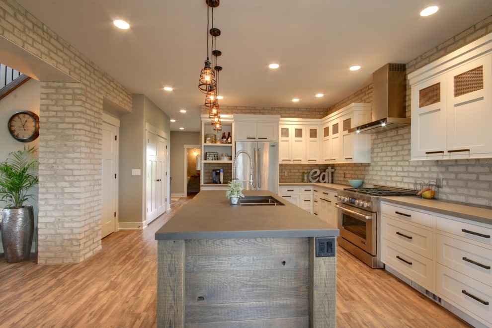 Inspiration for a mid-sized industrial l-shaped open plan kitchen in Grand Rapids with an undermount sink, recessed-panel cabinets, white cabinets, concrete benchtops, stainless steel appliances, vinyl floors and with island.